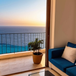 **

A cozy apartment interior in Sliema, Malta. Balcony overlooking the Mediterranean Sea. Modern furniture, warm lighting. Focus on a budget-friendly living space, reflecting affordable housing options in Malta.

**